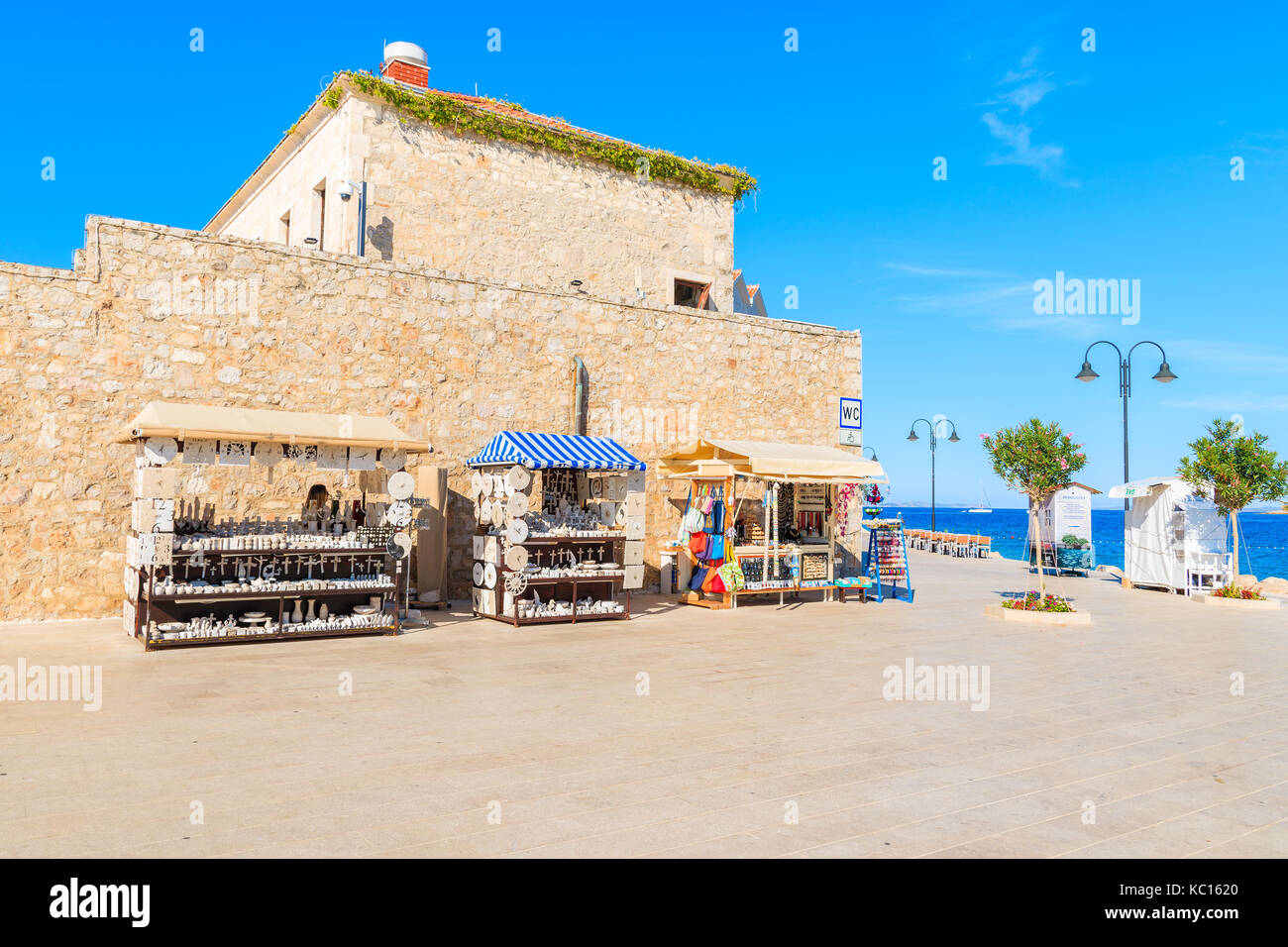 PRIMOSTEN, Croazia - Settembre 6, 2017: bancarelle con artigianato locale negozio di souvenir di fronte a old town gate in Primosten, Dalmazia, Croazia. Foto Stock