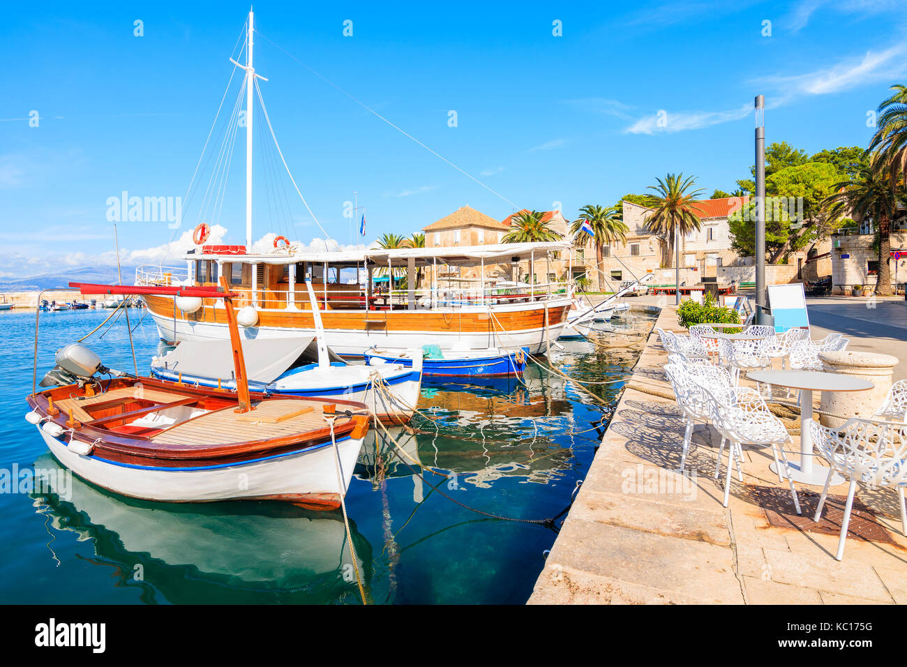 Barche da pesca e le sedie del locale cafe bar di sutivan porta, isola di Brac, Croazia Foto Stock