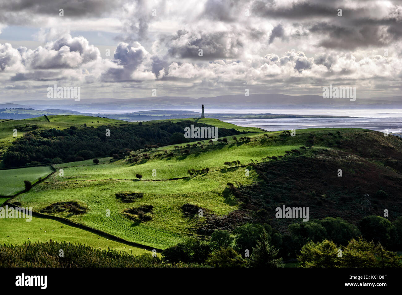 Vista in lontananza il faro hoad e morecambe bay presi dal modo in Cumbria con bassa sunshine evidenziando le colline circostanti Foto Stock