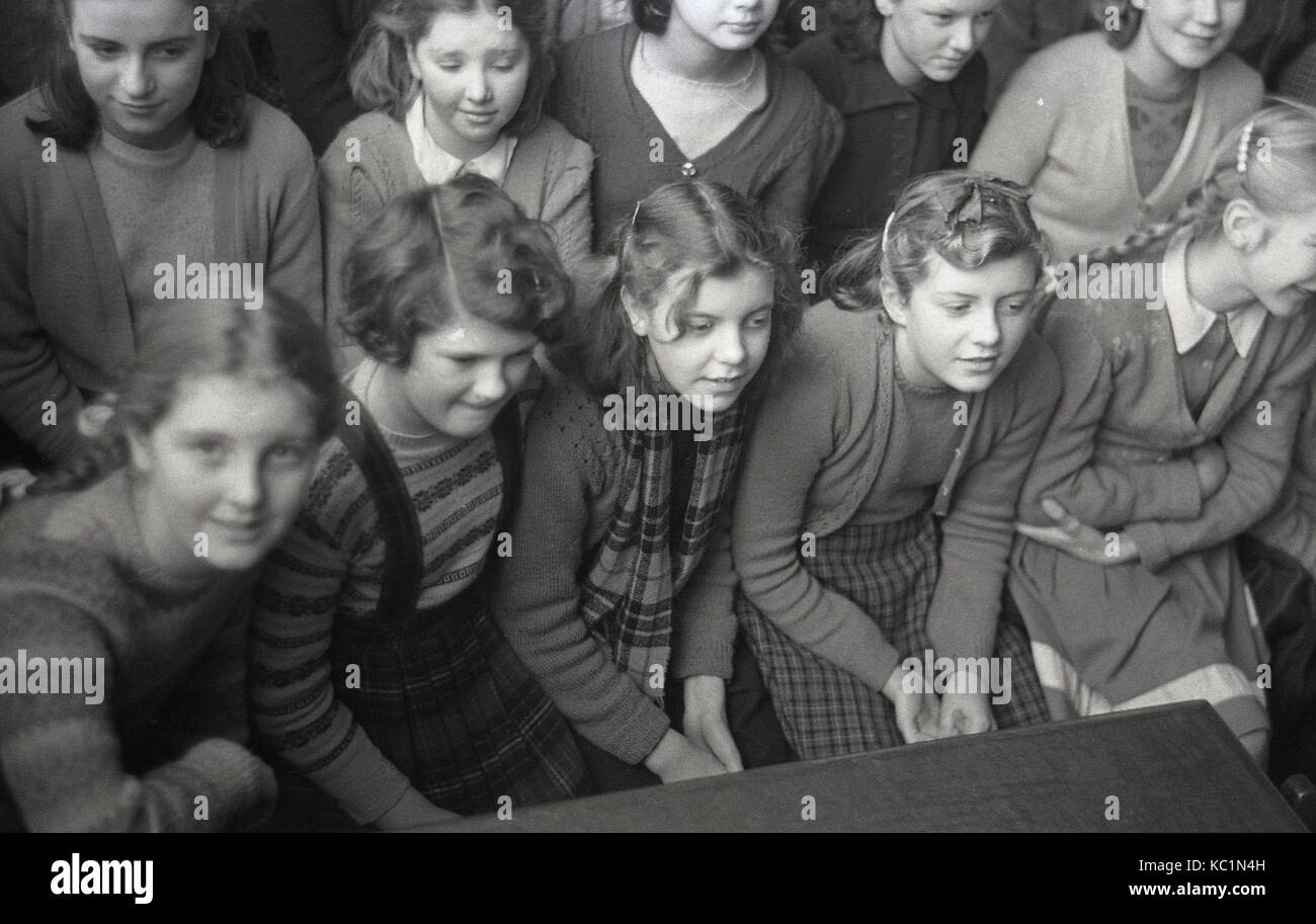 1948, storico, post-ww2 la Gran Bretagna con il razionamento alimentare, qui possiamo vedere la scuola inglese ragazze seduti insieme in una sala della scuola in attesa di ricevere un pacco alimentare (dono) dato alla scuola dal Comitato della Australian pacchi regalo regime. Foto Stock