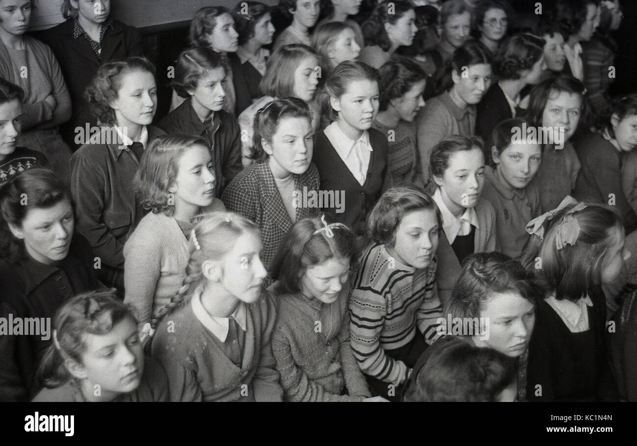 1948, storico, post-ww2 la Gran Bretagna con il razionamento alimentare, qui possiamo vedere la scuola inglese ragazze seduti insieme in una sala della scuola in attesa di ricevere un pacco alimentare (dono) dato alla scuola dal Comitato della Australian pacchi regalo regime. Foto Stock