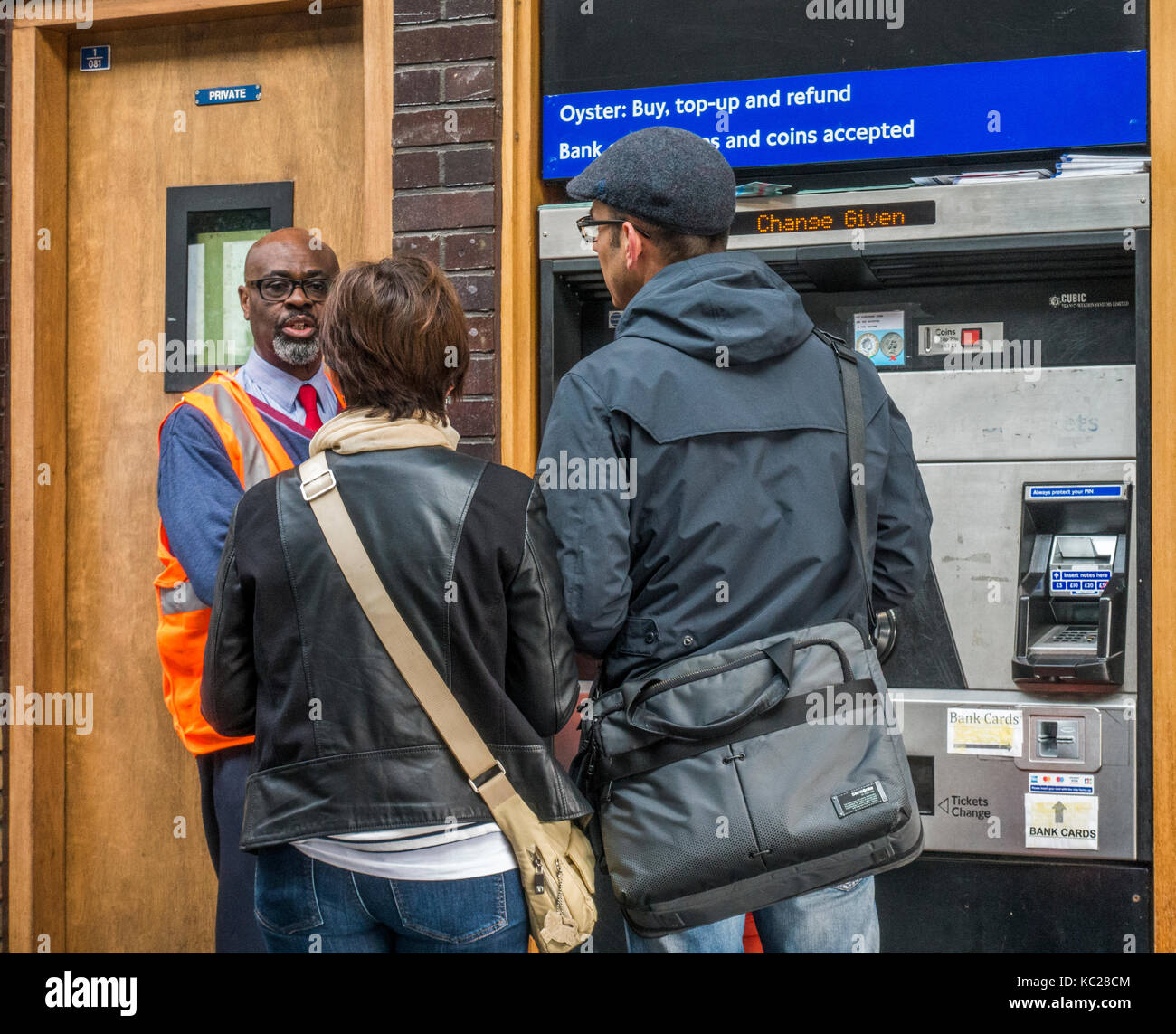 La metropolitana di Londra assistente utile consigliare due persone che acquistano i biglietti a South Ealing tube station, London W5, Inghilterra, Regno Unito. Foto Stock