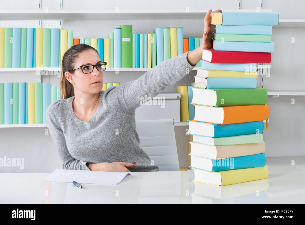 Giovane donna ignorando la risma di libro in biblioteca Foto Stock