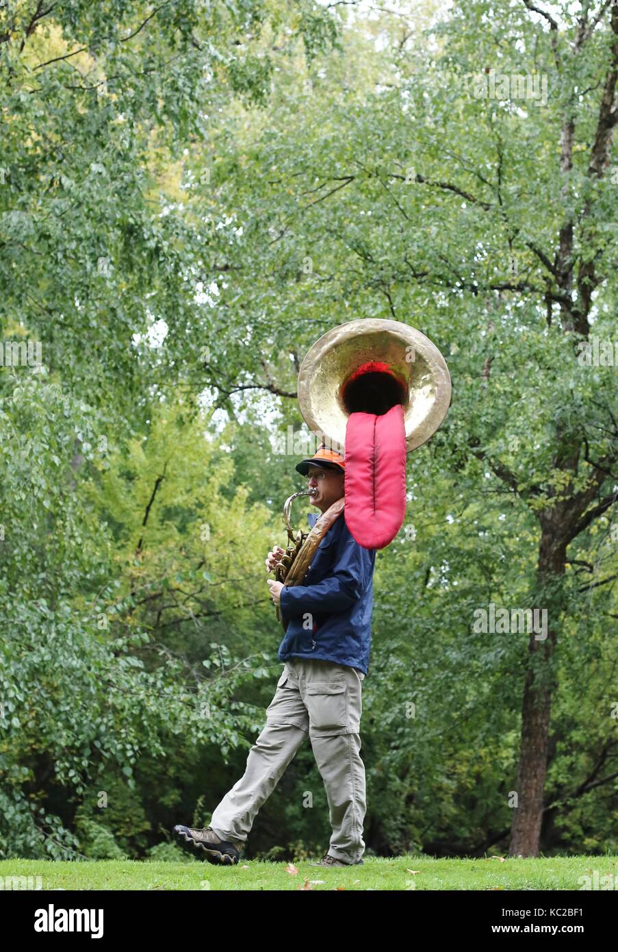 Un uomo giocando una tuba con una linguetta appendere fuori di esso, a Città Gemelle Maratona in Minneapolis, MN, Stati Uniti d'America. Foto Stock