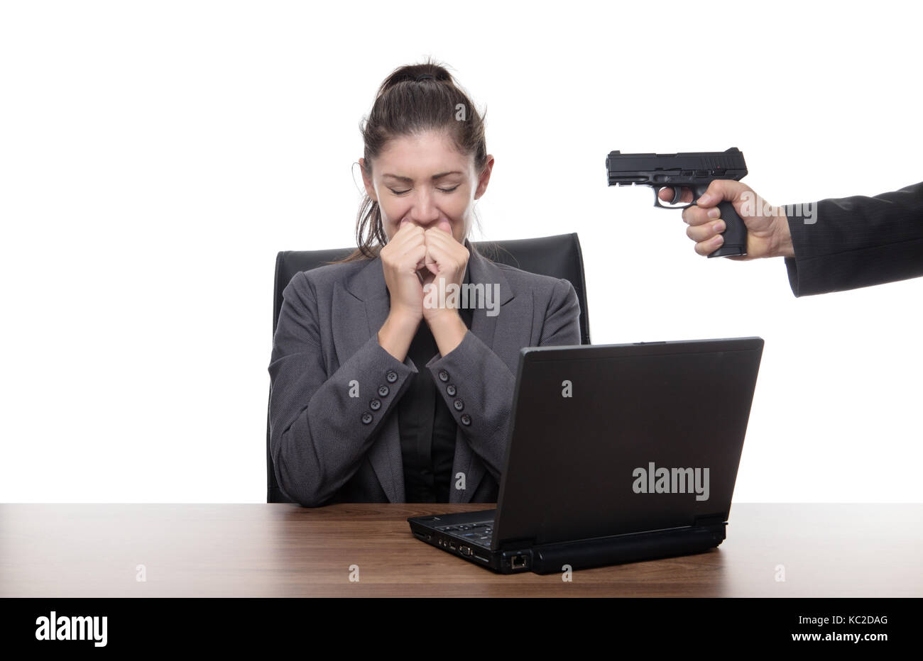 Business donna seduta alla sua scrivania con una pistola alla sua testa Foto Stock