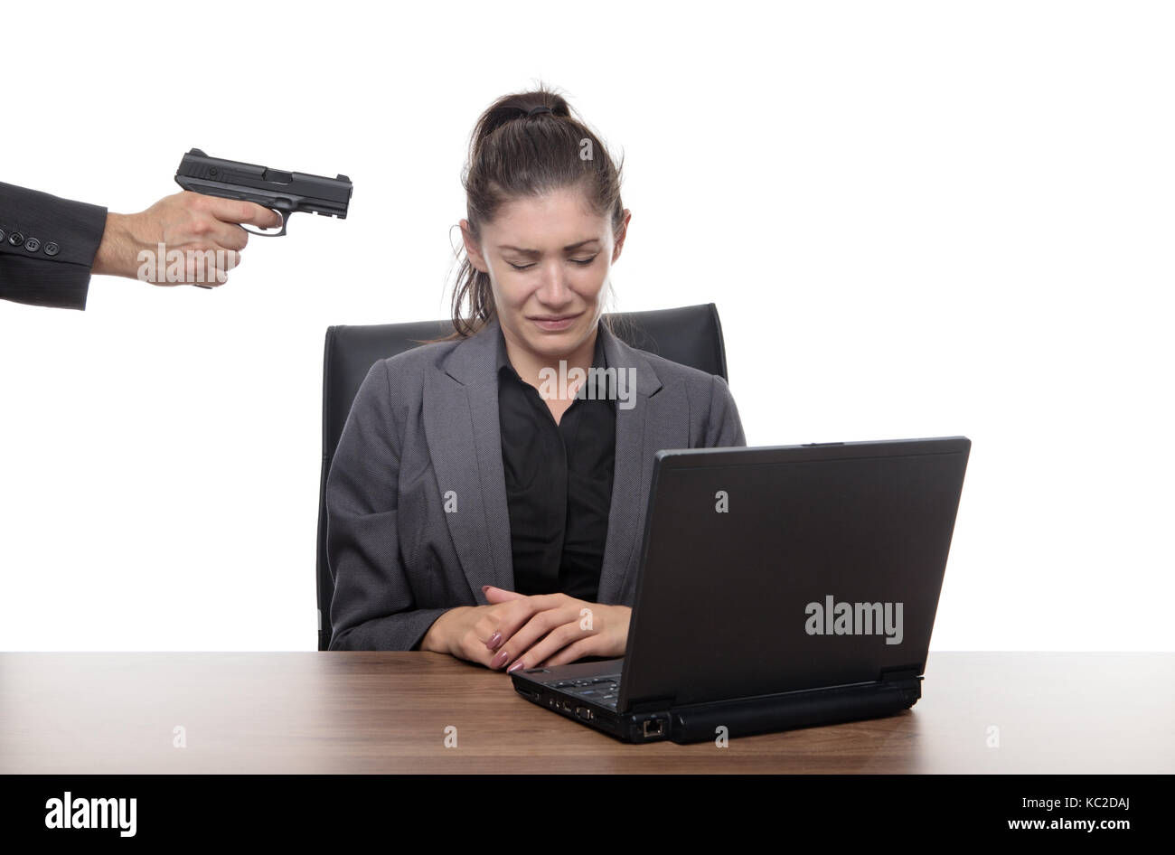 Business donna seduta alla sua scrivania con una pistola alla sua testa Foto Stock