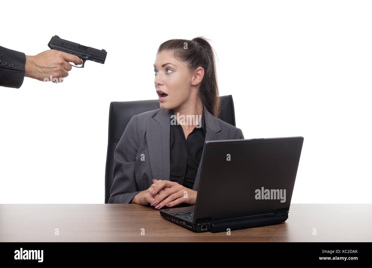 Business donna seduta alla sua scrivania con una pistola alla sua testa Foto Stock