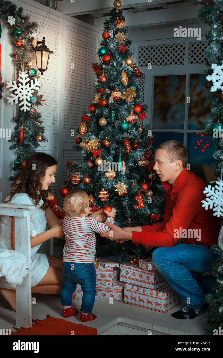 I genitori e il bambino vicino a un albero di natale. genitori aiutando la figlia decorare un albero di natale Foto Stock