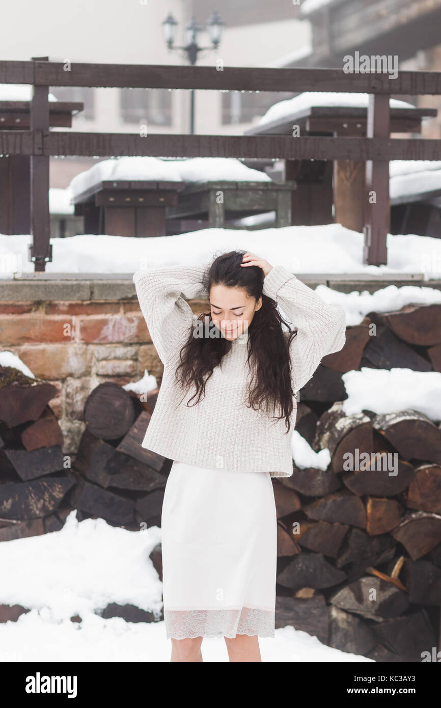 Donna con lunghi capelli neri nel caldo maglione di lana e un mantello realizzato in seta naturale con pizzo in posa all'aperto Foto Stock