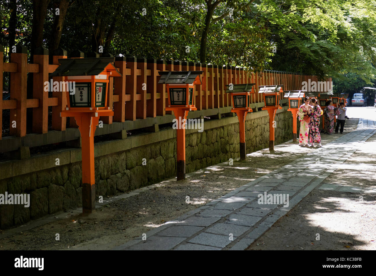 Kyoto, Giappone - 18 maggio 2017: Orange lanterne lungo il percorso a yasaka jinja santuario con donne in cammino in kimono Foto Stock