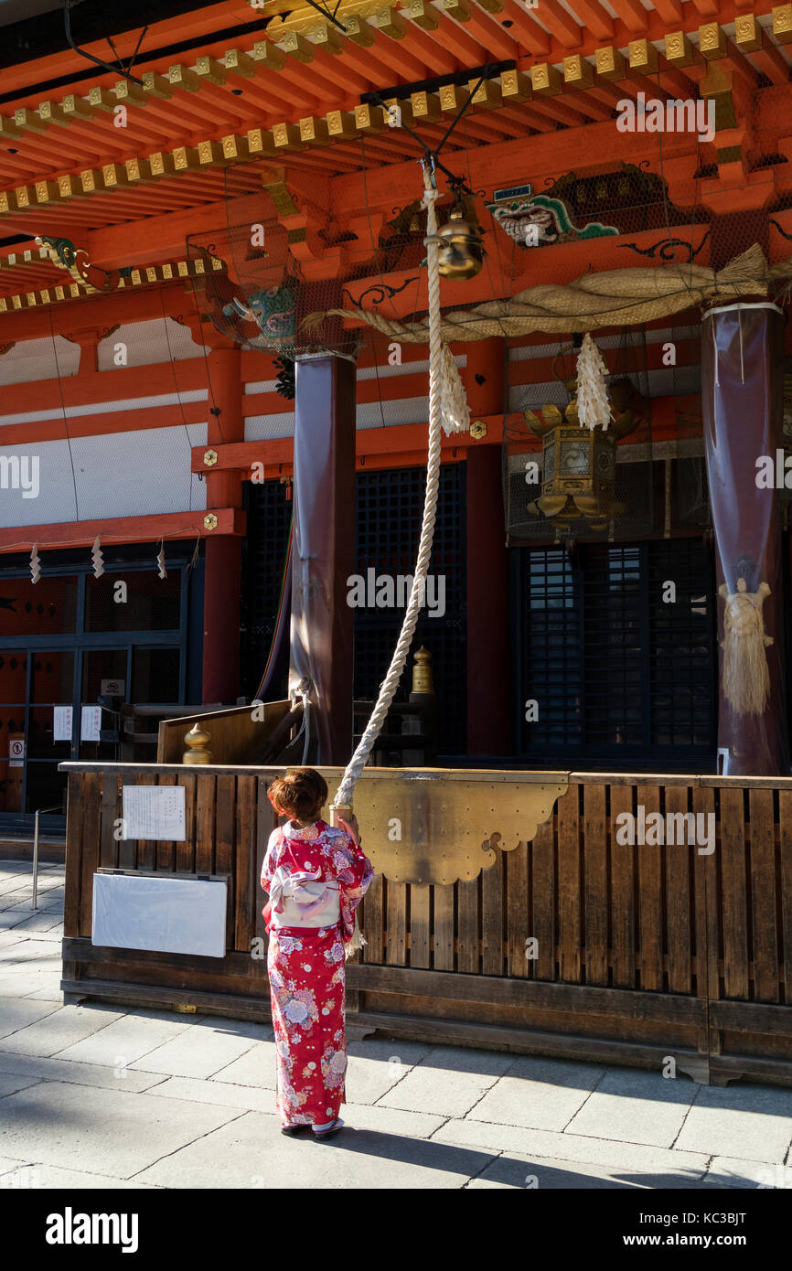 Kyoto, Giappone - 18 maggio 2017: donna in kimono tirando la campana-fune come segno di devozione al yasaka jinja santuario in kyoto Foto Stock