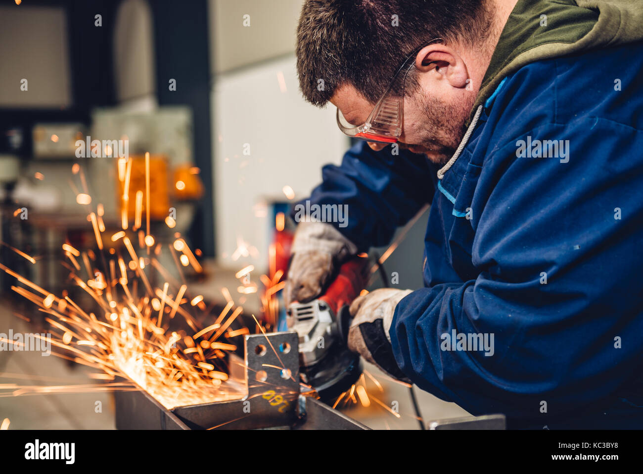 Lavoratore utilizzando smerigliatrice angolare in fabbrica e gettando scintille Foto Stock