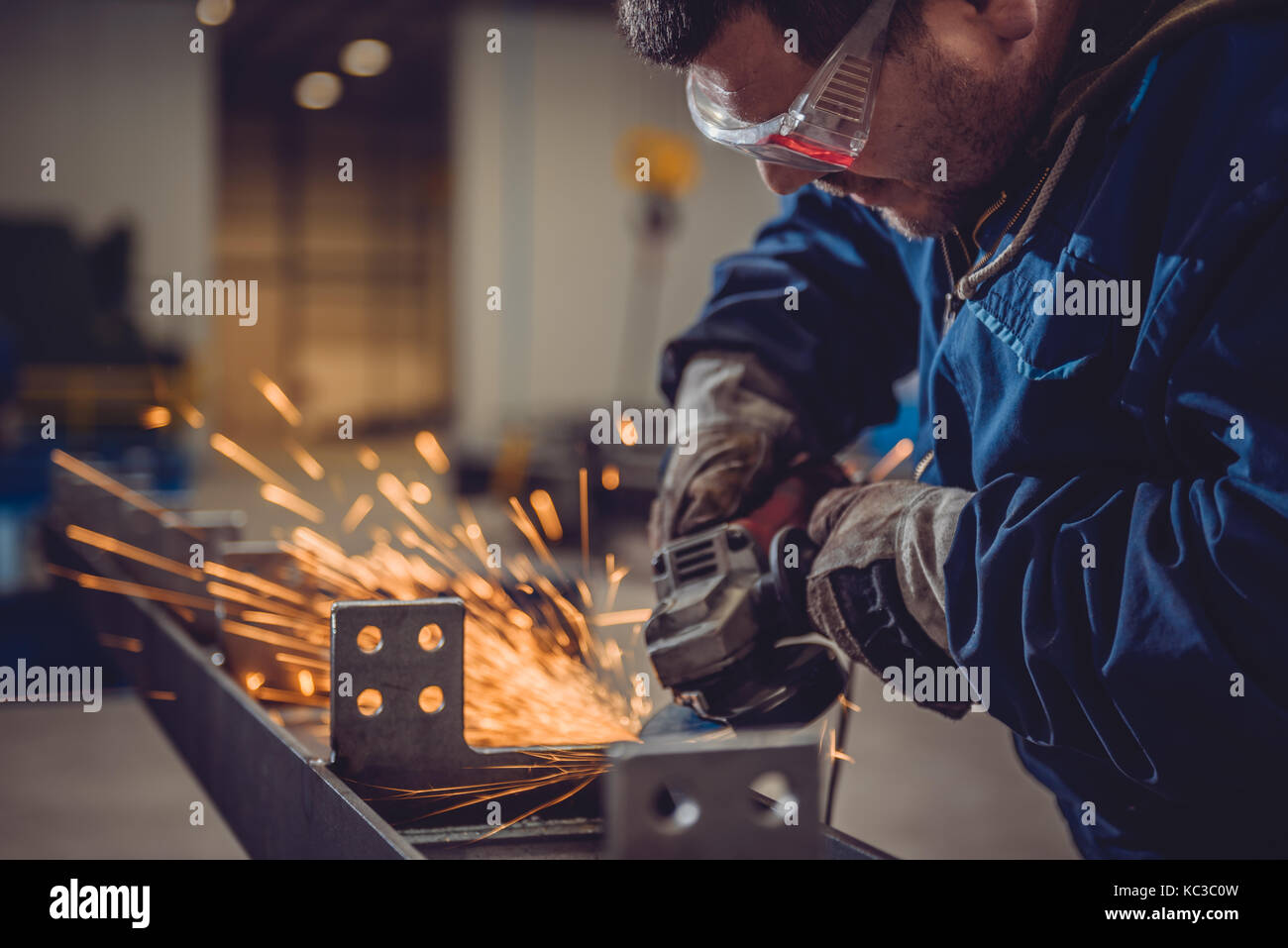 Lavoratore utilizzando smerigliatrice angolare in fabbrica e gettando scintille Foto Stock