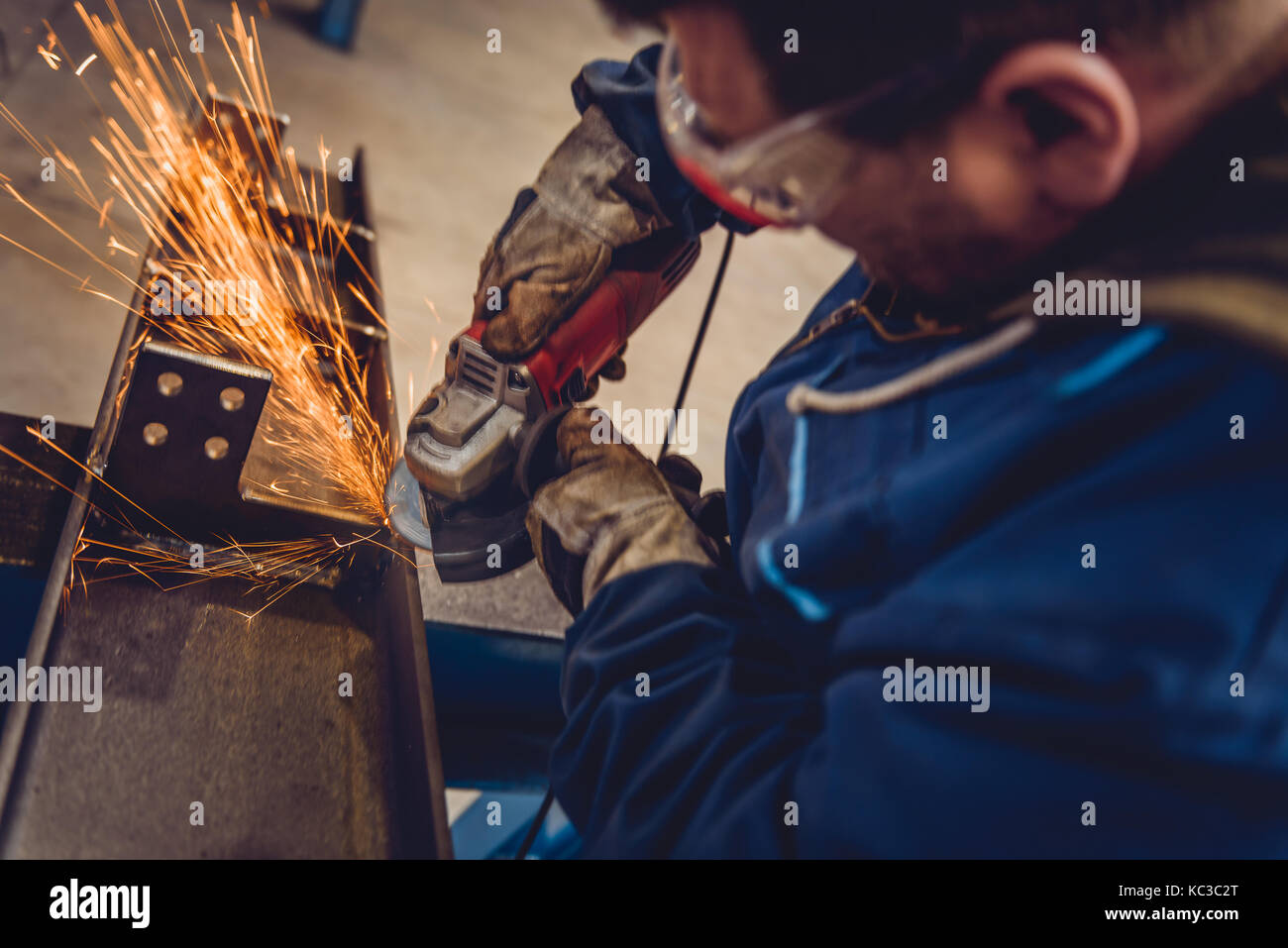 Lavoratore utilizzando smerigliatrice angolare in fabbrica e gettando scintille Foto Stock