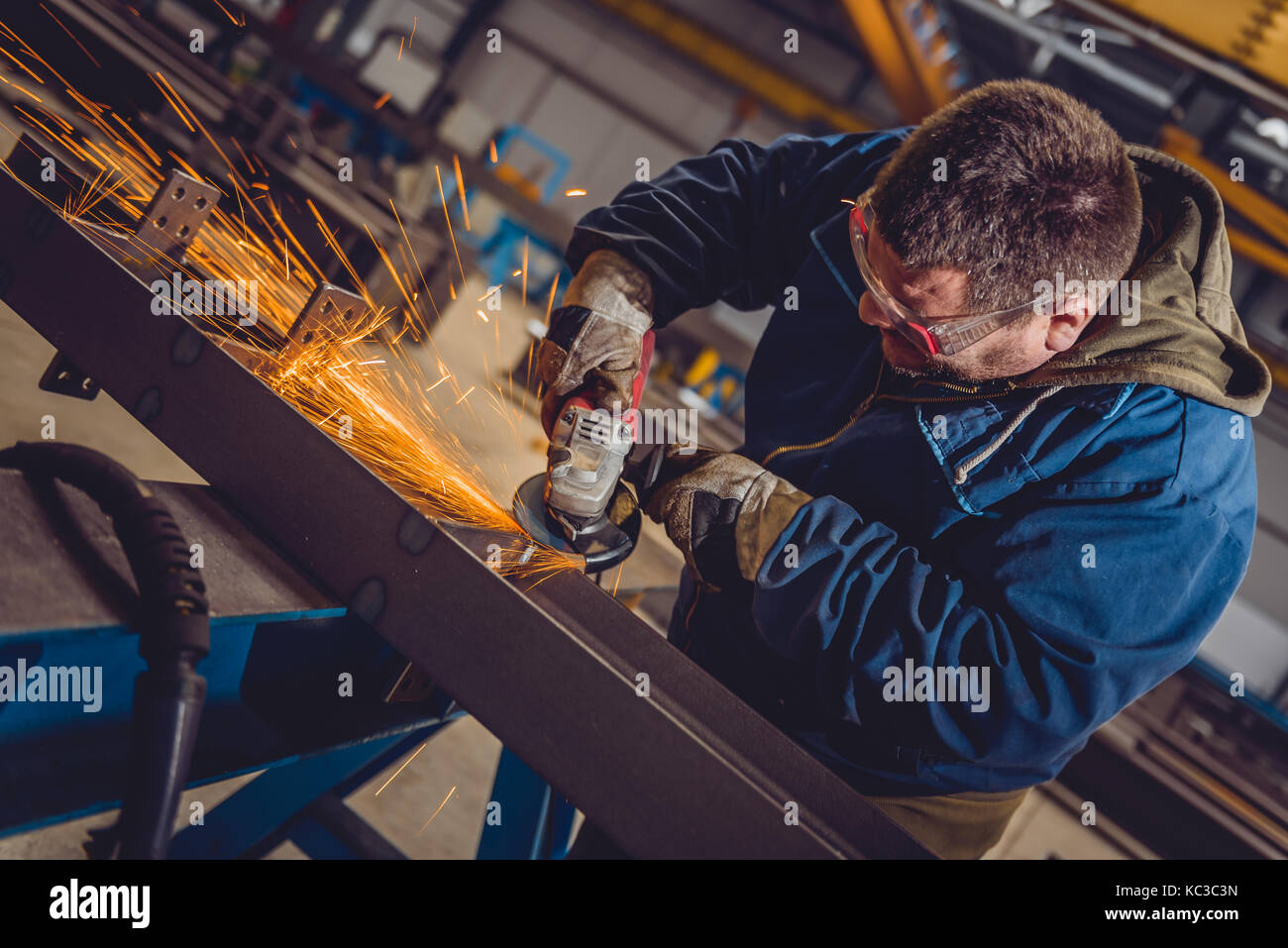 Lavoratore utilizzando smerigliatrice angolare in fabbrica e gettando scintille Foto Stock