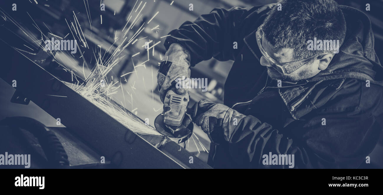 Lavoratore utilizzando smerigliatrice angolare in fabbrica e gettando scintille Foto Stock