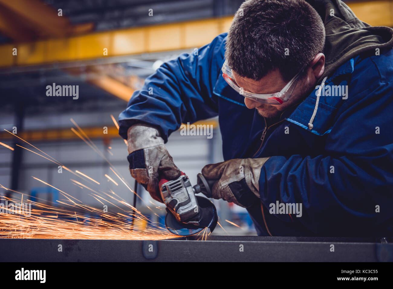 Lavoratore utilizzando smerigliatrice angolare in fabbrica e gettando scintille Foto Stock