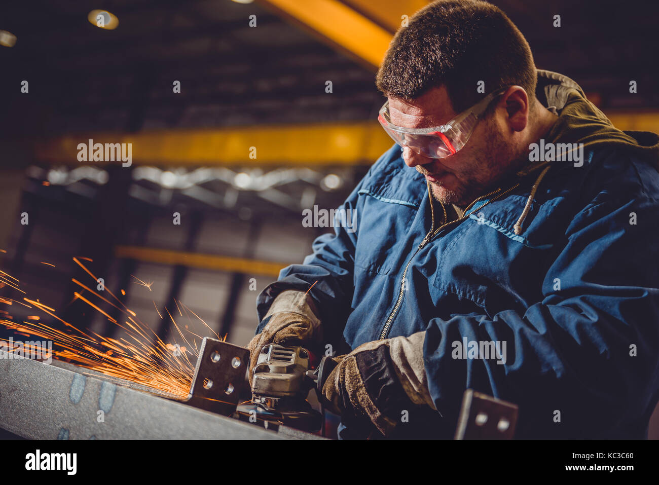 Lavoratore utilizzando smerigliatrice angolare in fabbrica e gettando scintille Foto Stock