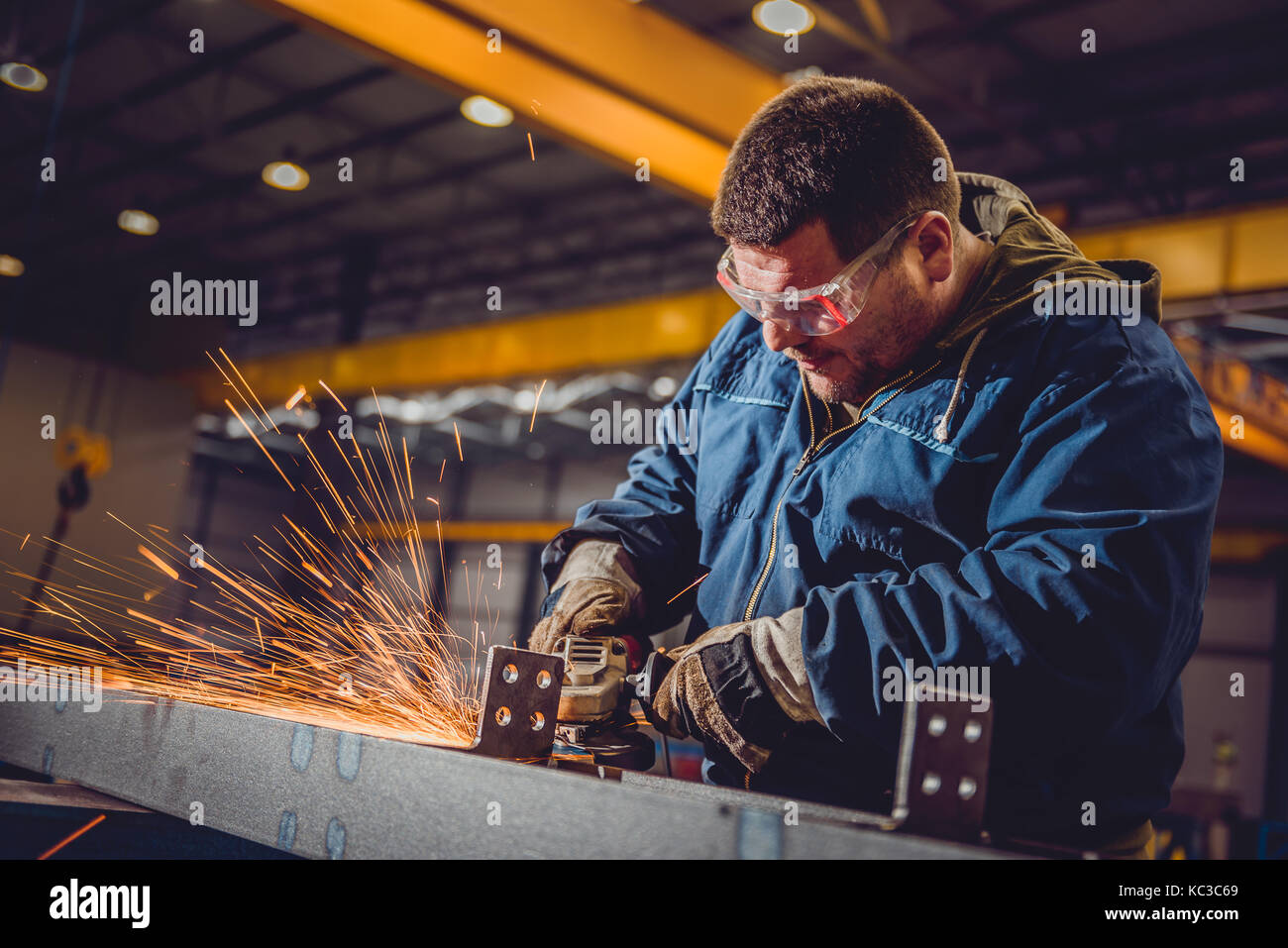 Lavoratore utilizzando smerigliatrice angolare in fabbrica e gettando scintille Foto Stock