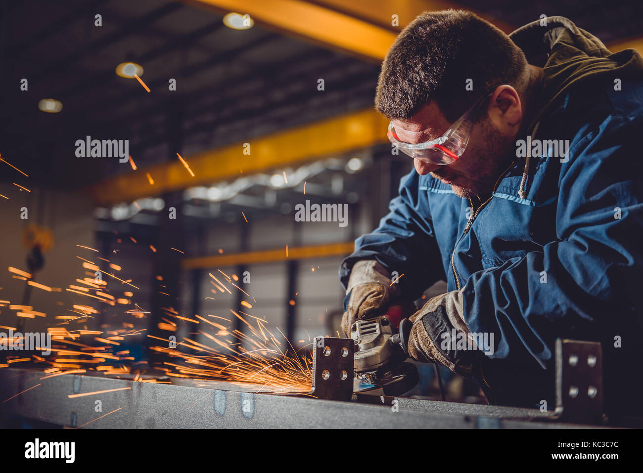 Lavoratore utilizzando smerigliatrice angolare in fabbrica e gettando scintille Foto Stock
