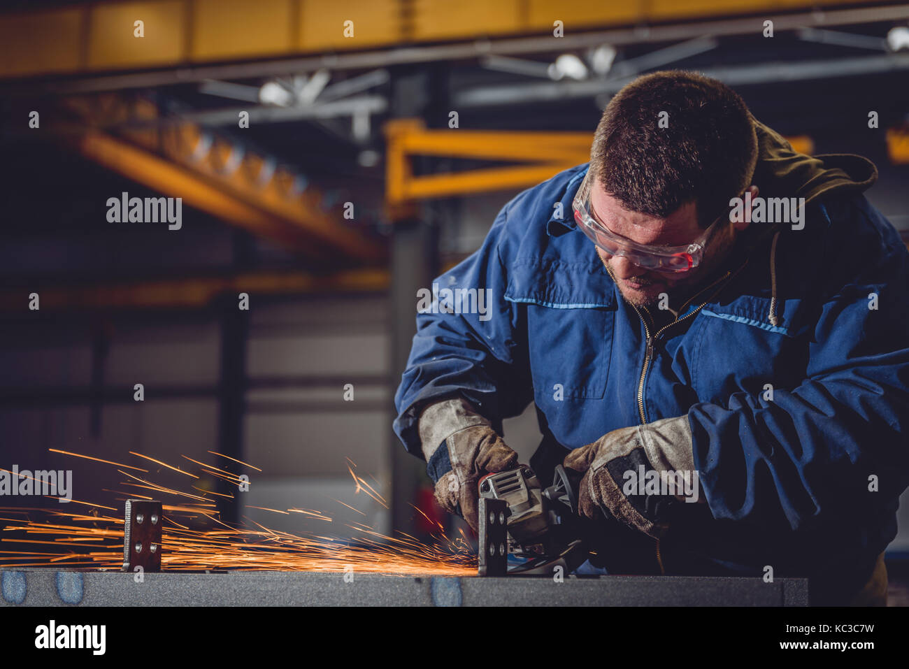 Lavoratore utilizzando smerigliatrice angolare in fabbrica e gettando scintille Foto Stock