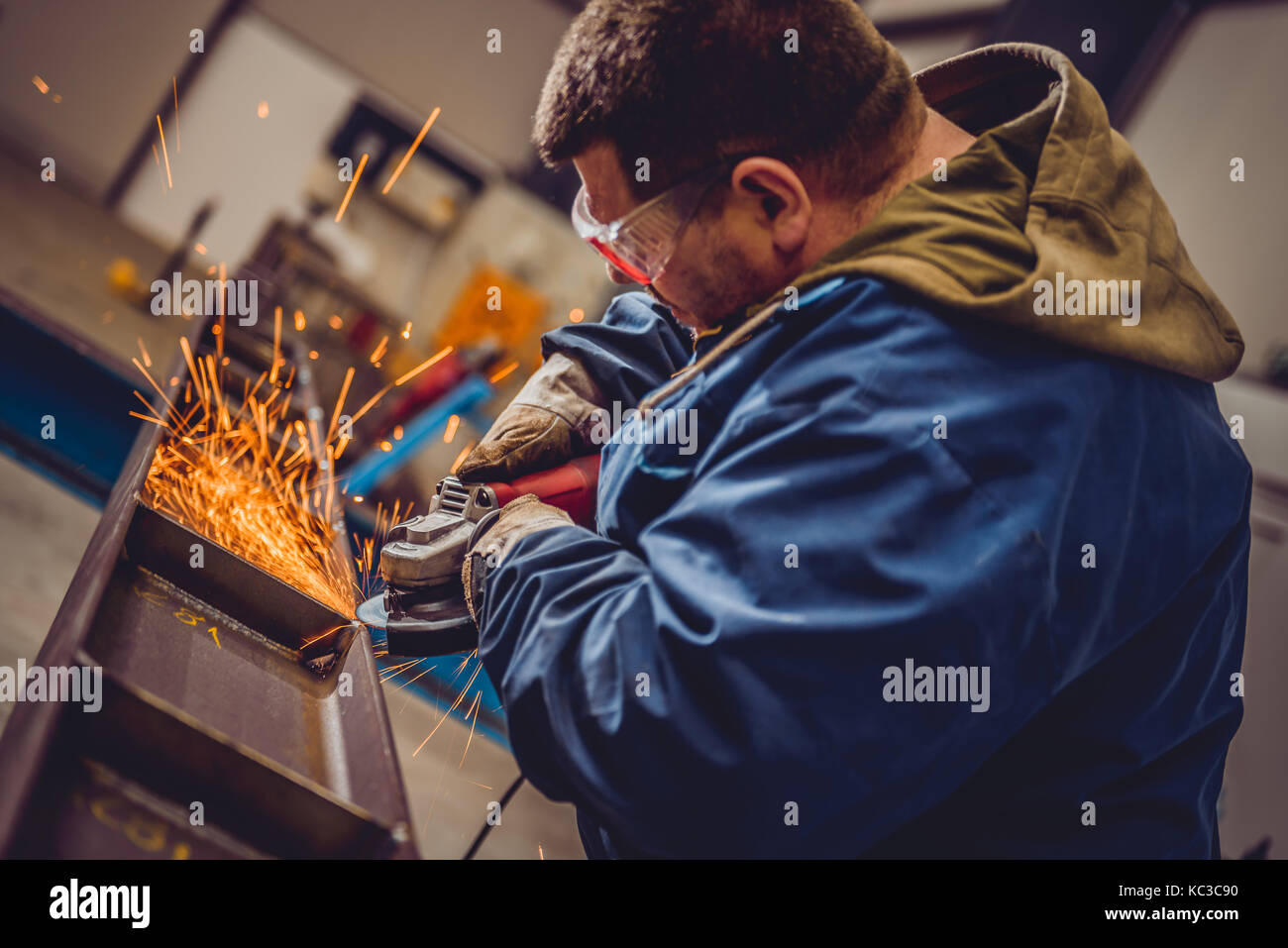 Lavoratore utilizzando smerigliatrice angolare in fabbrica e gettando scintille Foto Stock