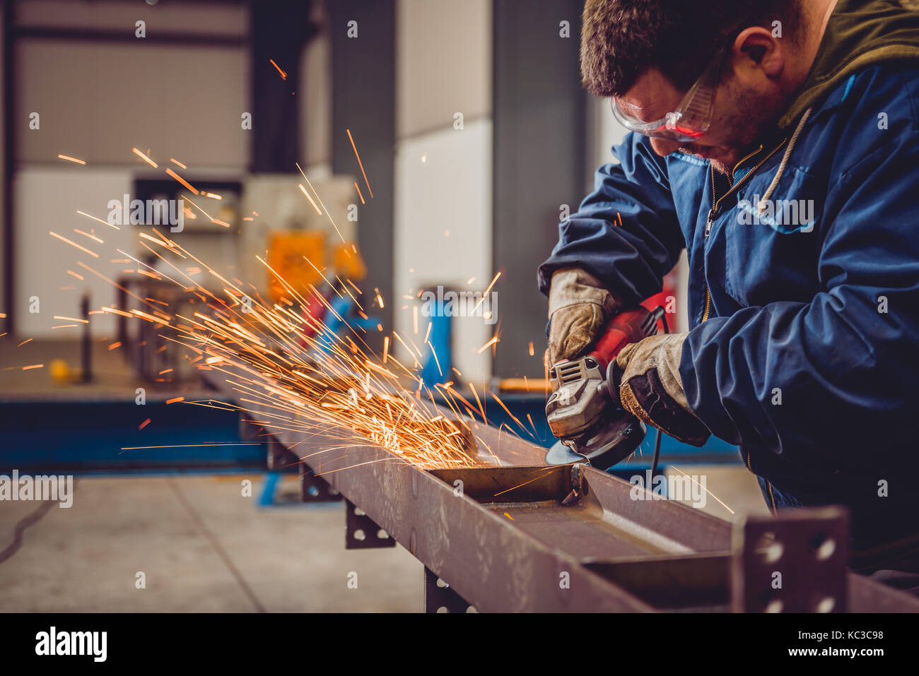 Lavoratore utilizzando smerigliatrice angolare in fabbrica e gettando scintille Foto Stock