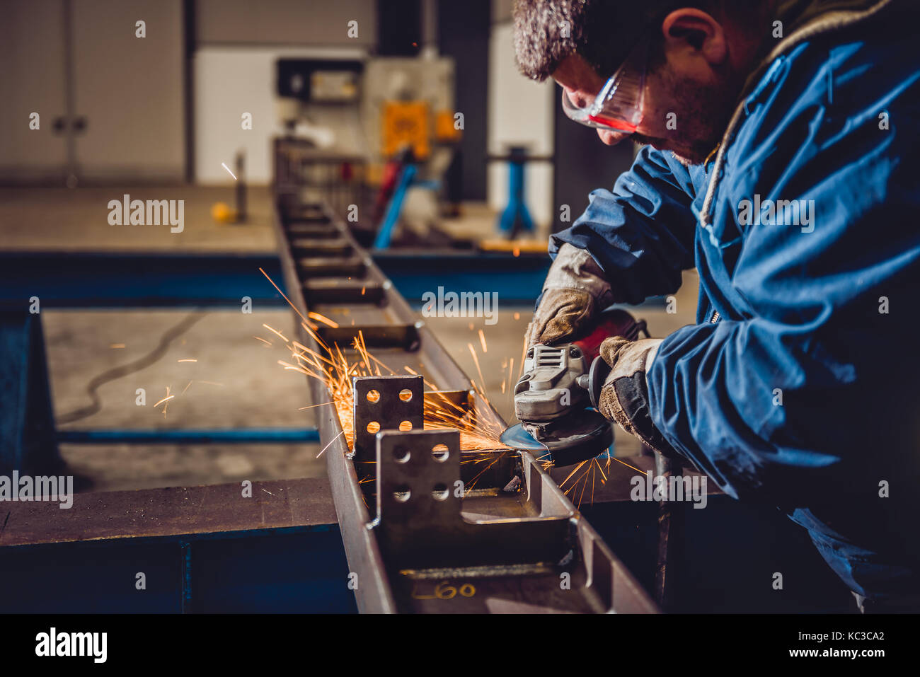 Lavoratore utilizzando smerigliatrice angolare in fabbrica e gettando scintille Foto Stock