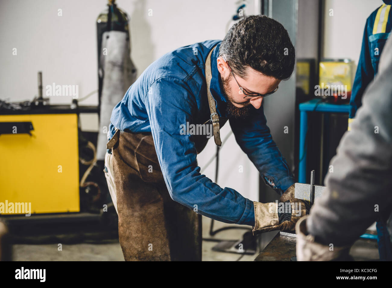 Saldatore controllo angolo di materiali saldati in officina Foto Stock