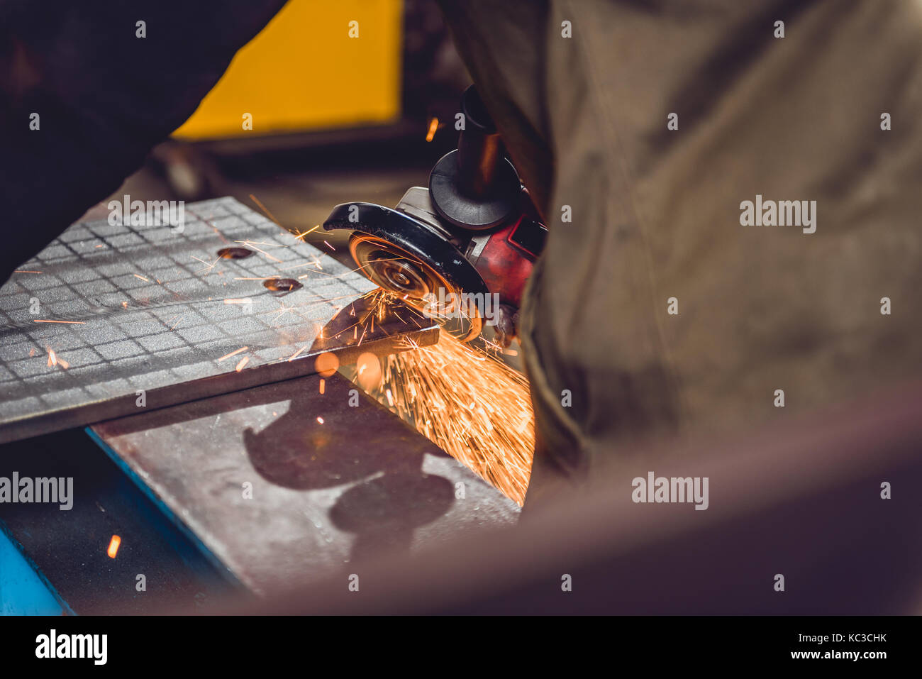 Lavoratore utilizzando smerigliatrice angolare in fabbrica e gettando scintille Foto Stock