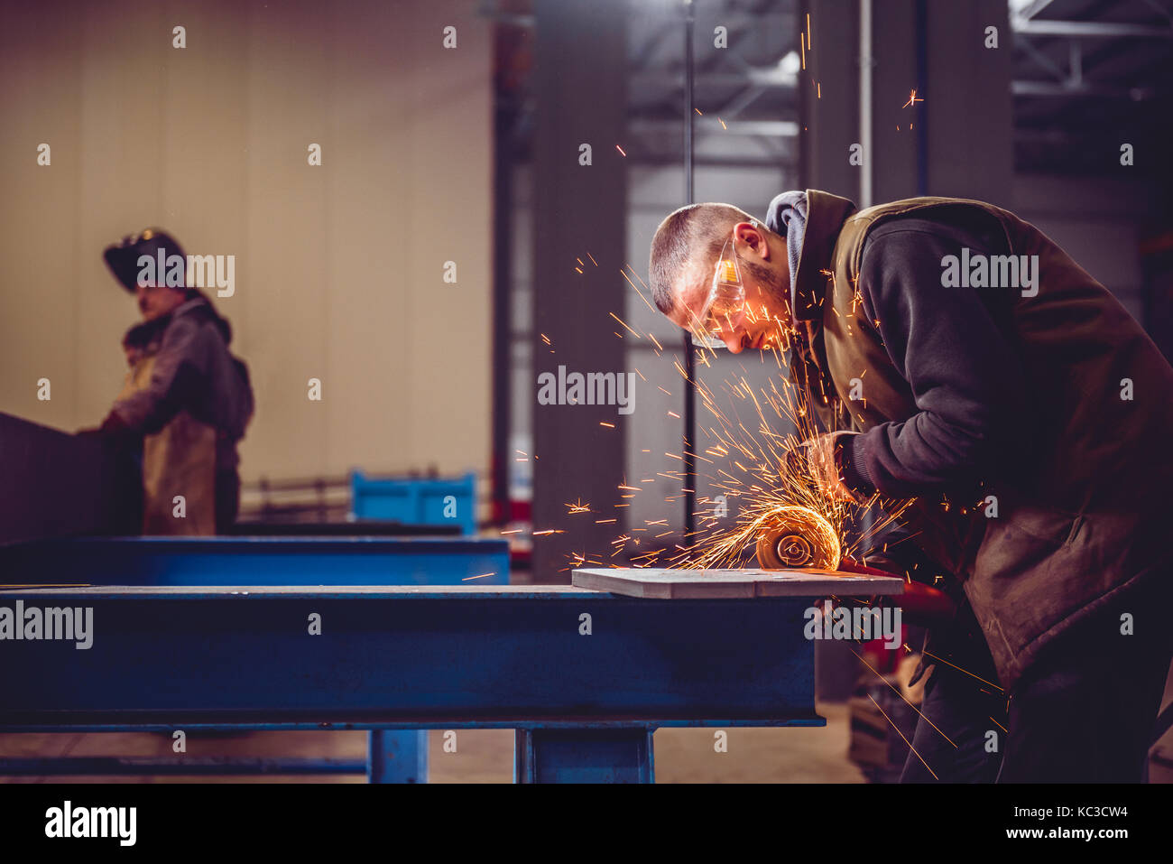 Lavoratore utilizzando smerigliatrice angolare in fabbrica e gettando scintille Foto Stock
