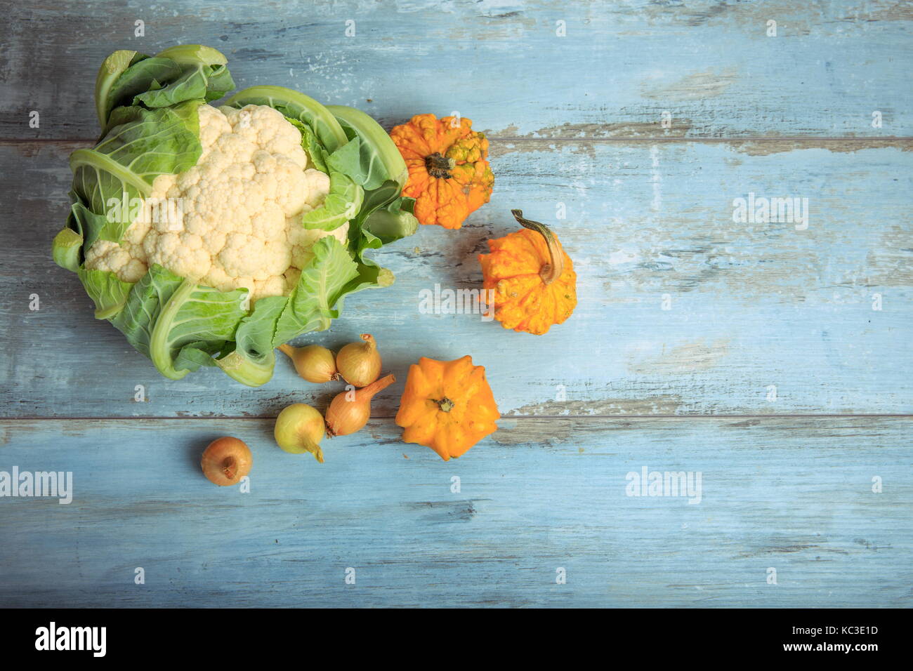 La zucca decorativa, cavolfiori e cipolle su un rustico in legno di colore blu sullo sfondo. il mangiare sano, concetto vegetariano. Foto Stock