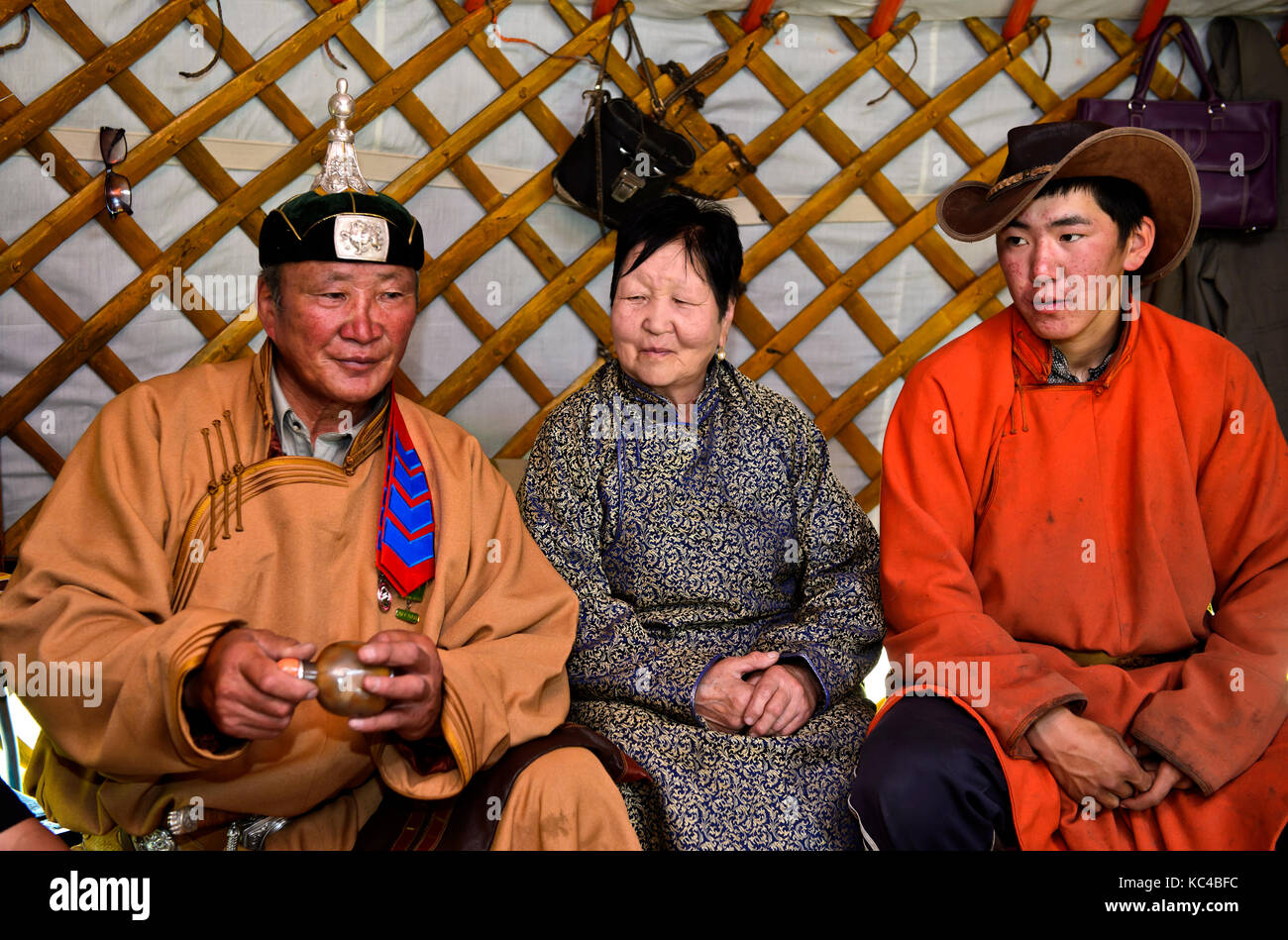 A casa di pastori Mongoli, padre, madre e figlio in un tradizionale yurt, uomo in possesso di una tradizionale bottiglia di tabacco da fiuto, huurug, nelle sue mani, mongo Foto Stock