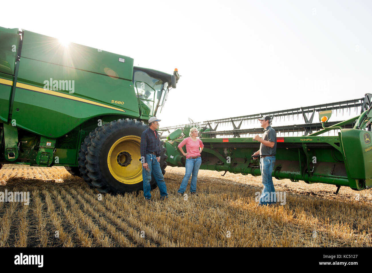 Un giovane agricoltore femmina colloqui con assunto le mani, così come un specialista di gps, prima di uscire per il raccolto del frumento su l'azienda agricola di famiglia a Breckenridge, n Foto Stock