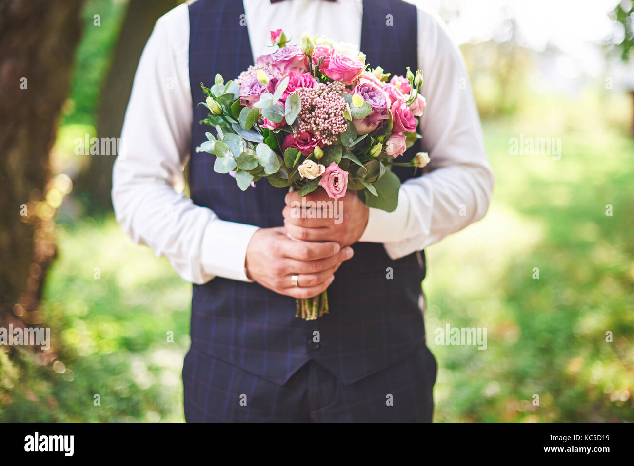 Elegante groom tenendo una gara rosa bouquet di nozze Foto Stock