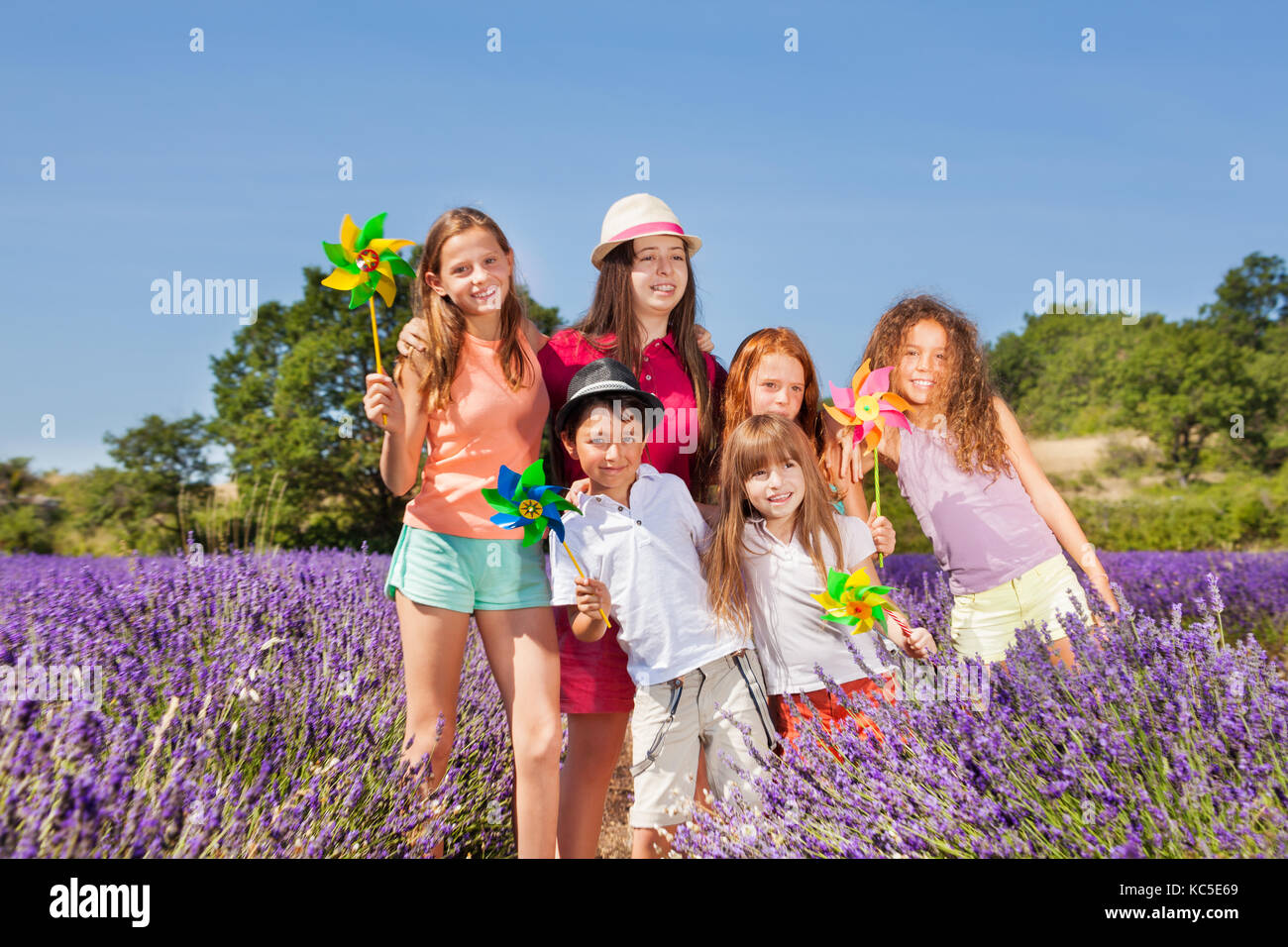Felice preteen ragazze e ragazzi giocare con pinwheels nel campo di lavanda Foto Stock