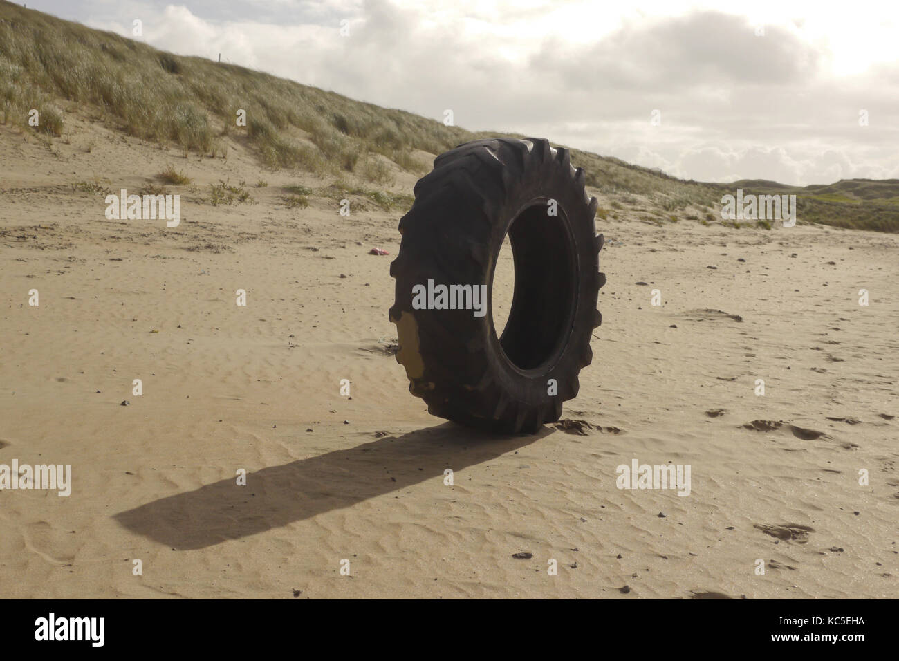 Un pneumatico sulla spiaggia. Un grande massiccio pneumatico è impostato allentato su una spiaggia in Irlanda, origine sconosciuta. Foto Stock