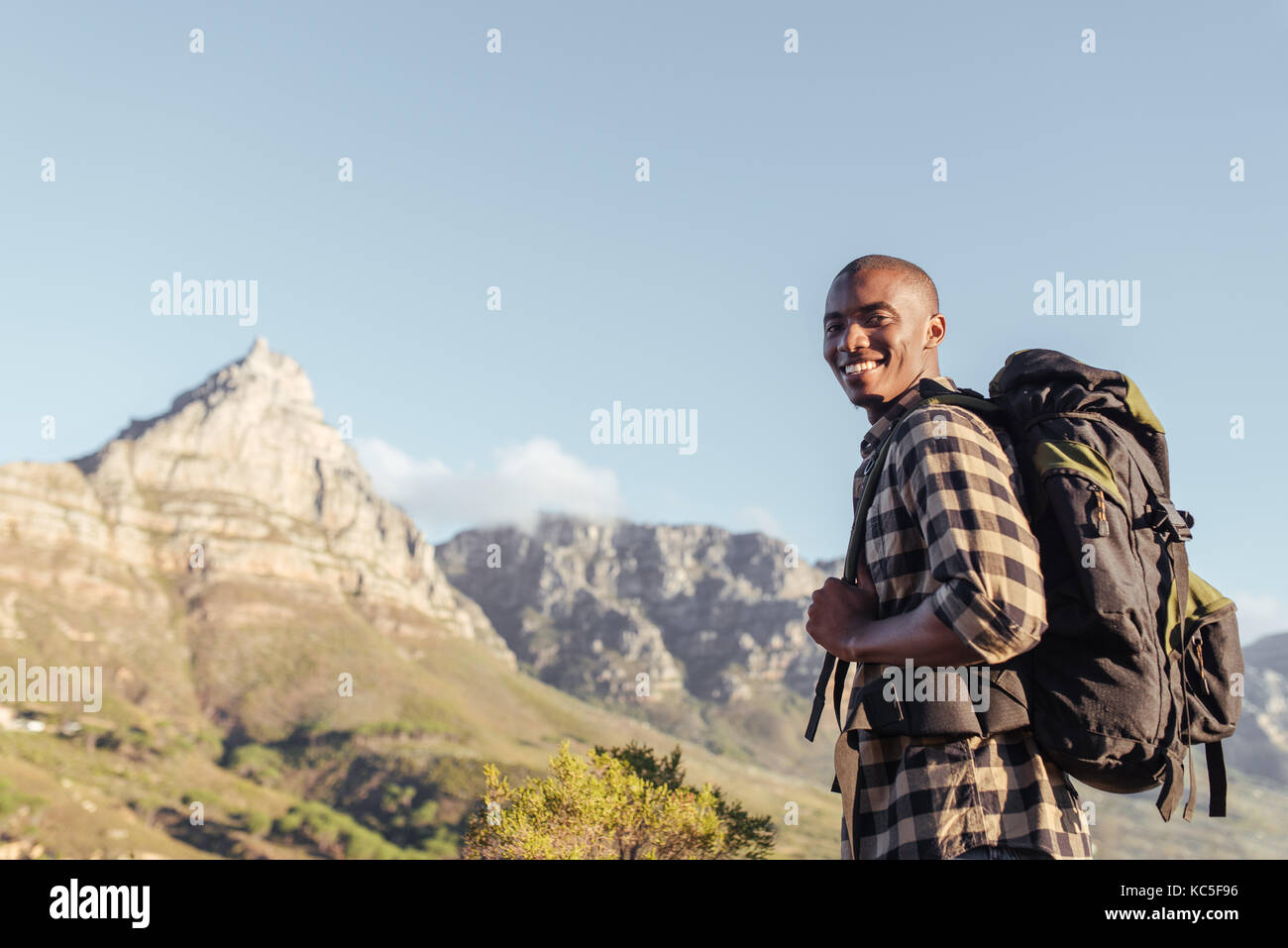 Sorridente giovane africano godendo la vista mentre fuori escursionismo Foto Stock