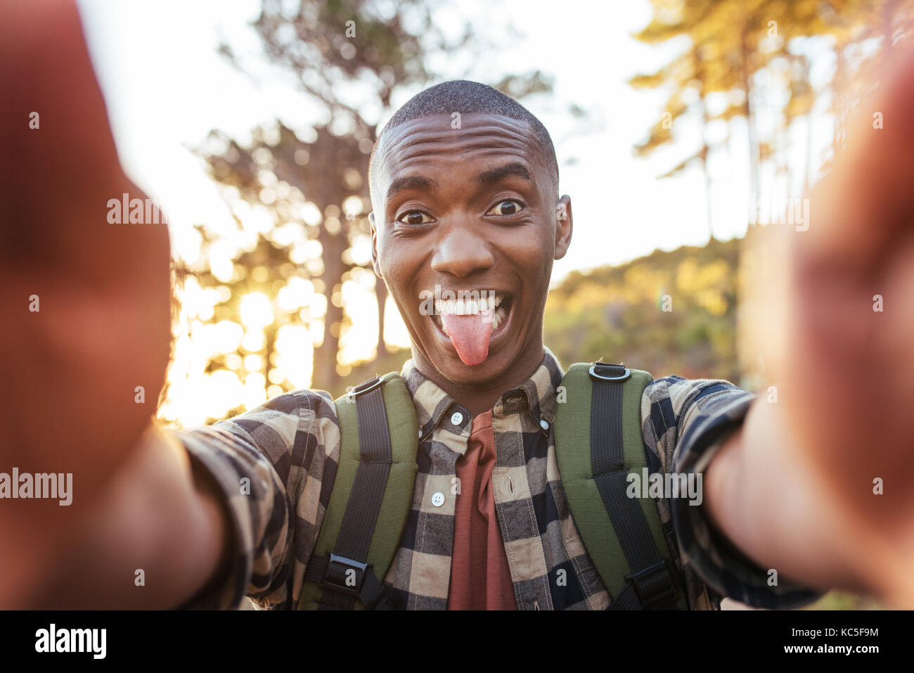 Giovane africano rendendo volti e tenendo selfies all'aperto Foto Stock