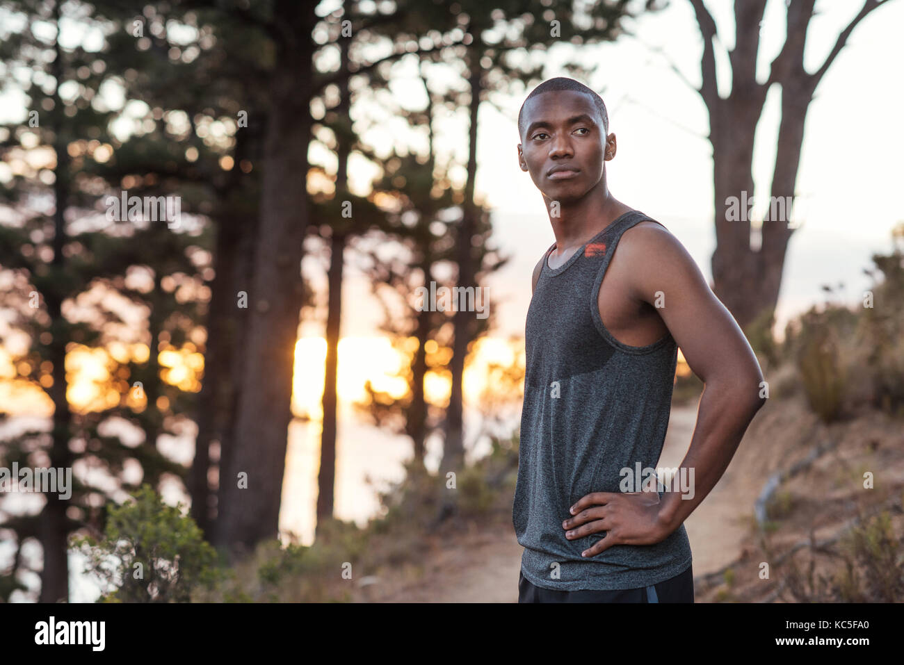 Montare l'uomo africano in piedi su un sentiero mentre jogging Foto Stock