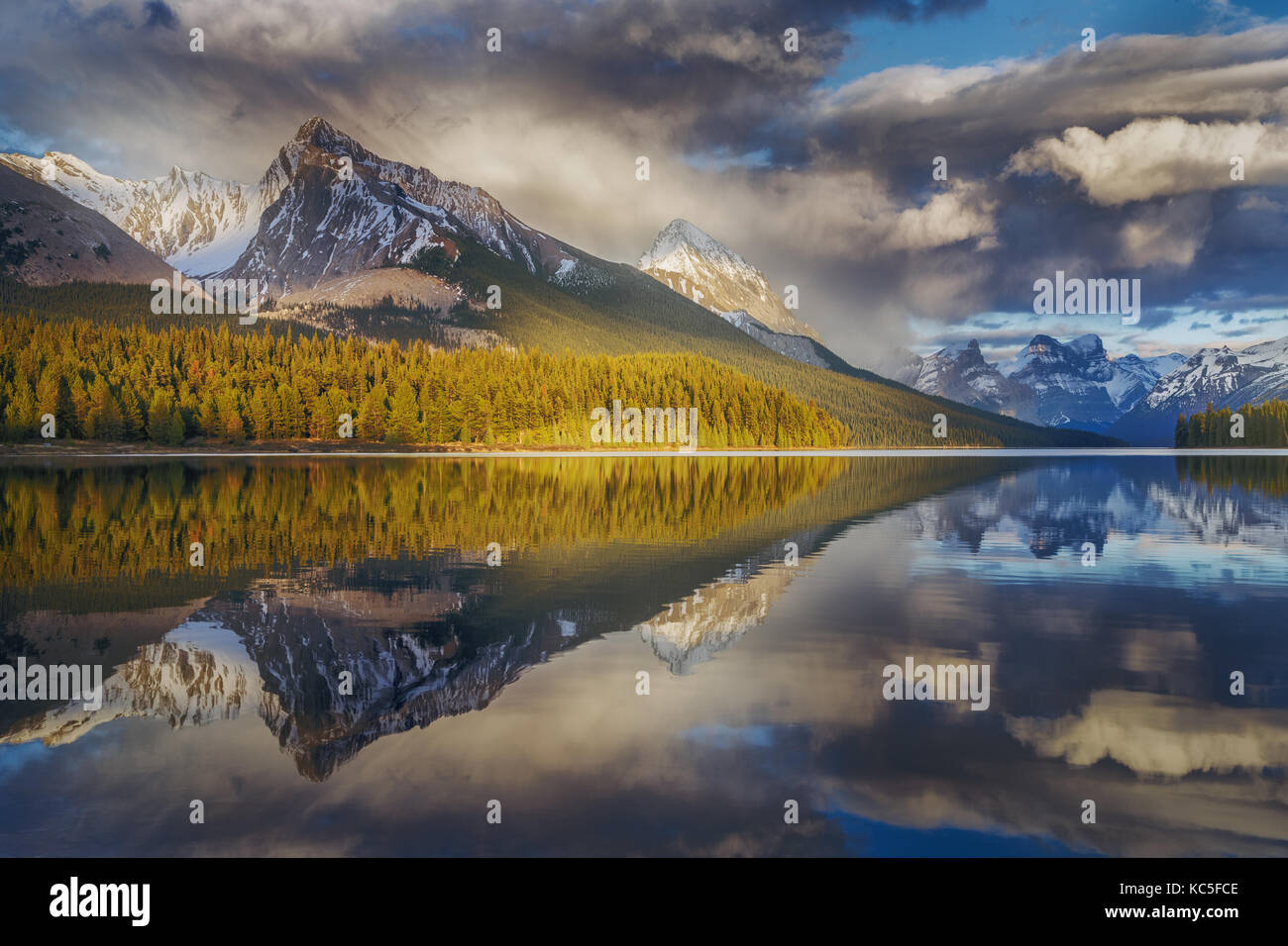 La montagna e la sua riflessione disegno la forma di una freccia nel Lago Maligne con drammatica cielo nuvoloso. Canada paesaggio. Riflessioni a specchio. Foto Stock