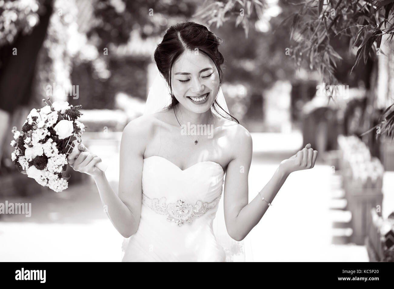 Giovane e bella sposa asiatici esultanza con bouquet in mano, in bianco e nero. Foto Stock