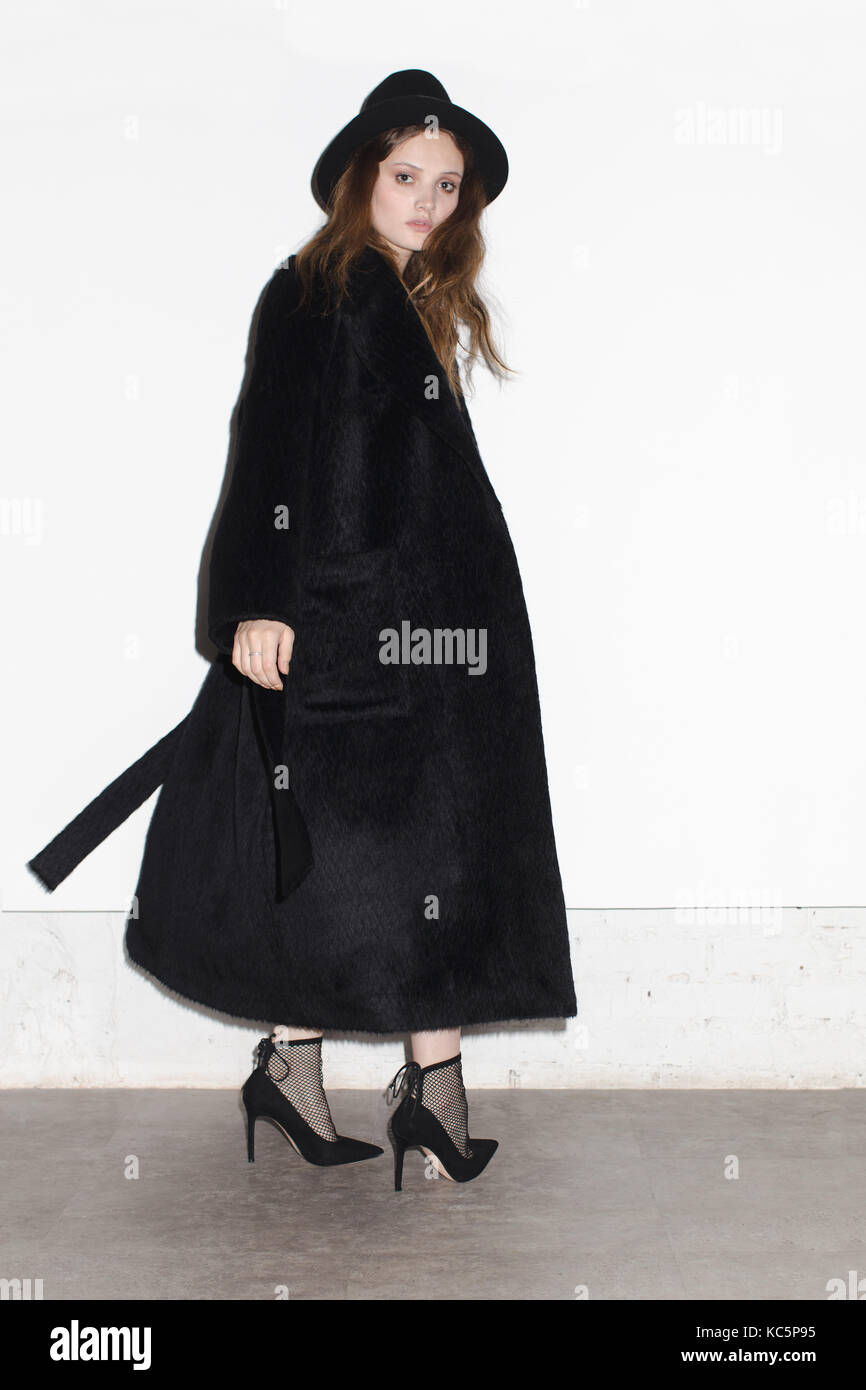 Elegante modello in lungo cappotto nero su sfondo bianco Foto Stock