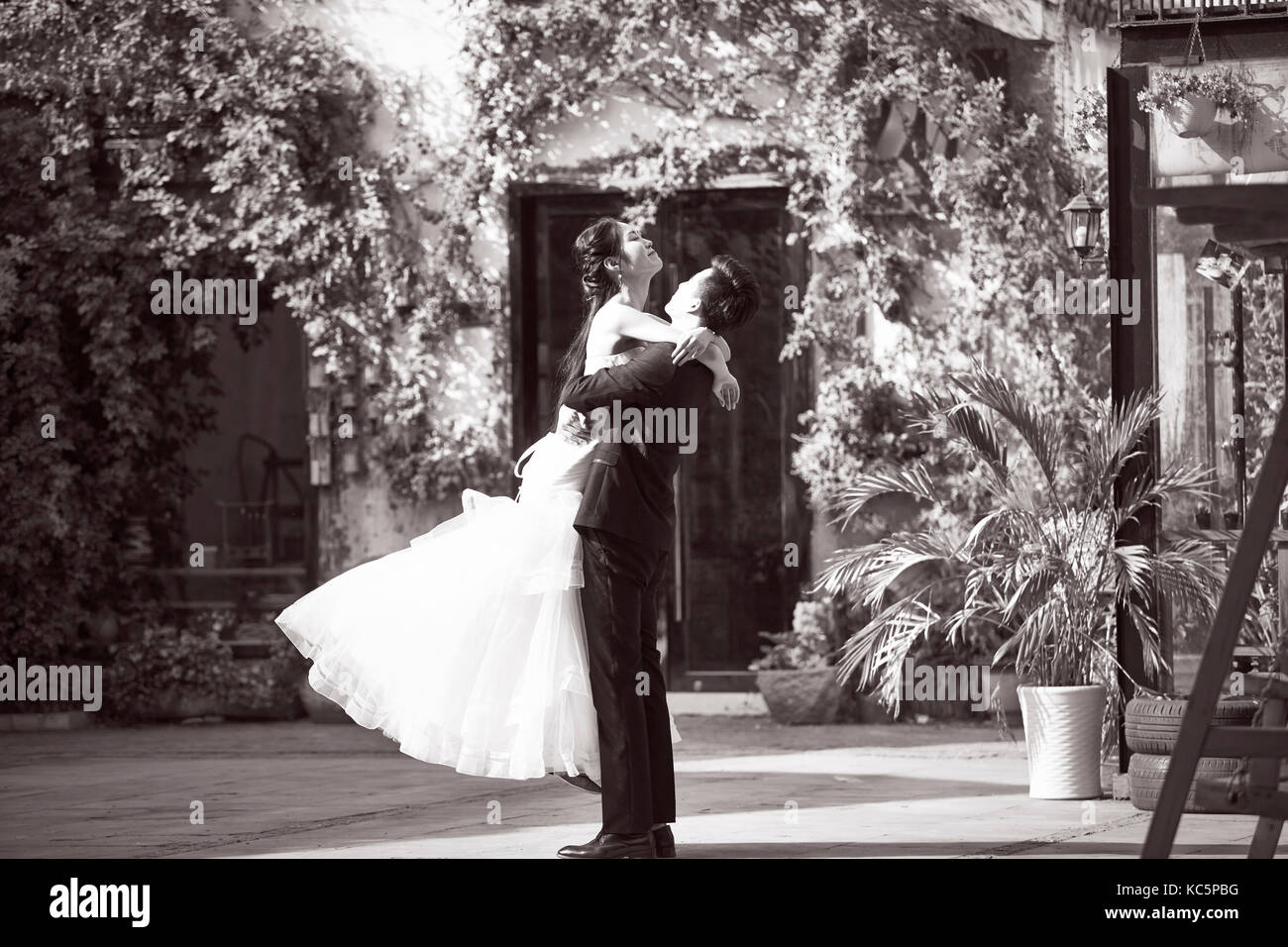 Asian sposi sposa e lo sposo per celebrare il matrimonio al di fuori di un edificio, in bianco e nero. Foto Stock