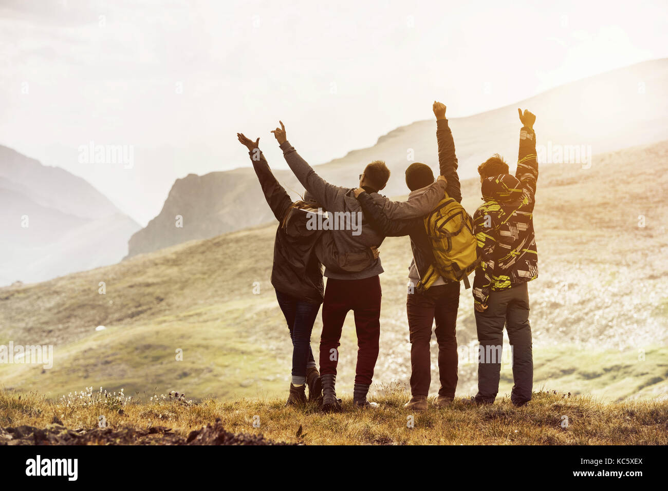 Quattro amici divertendosi tramonti sulle montagne Foto Stock