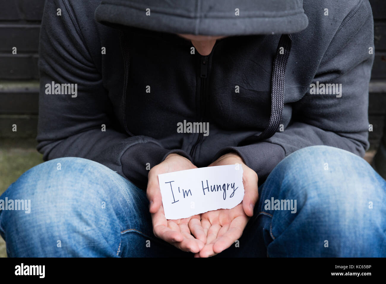 Pezzo di carta bianca con il testo che sono affamati in mano d'uomo Foto Stock