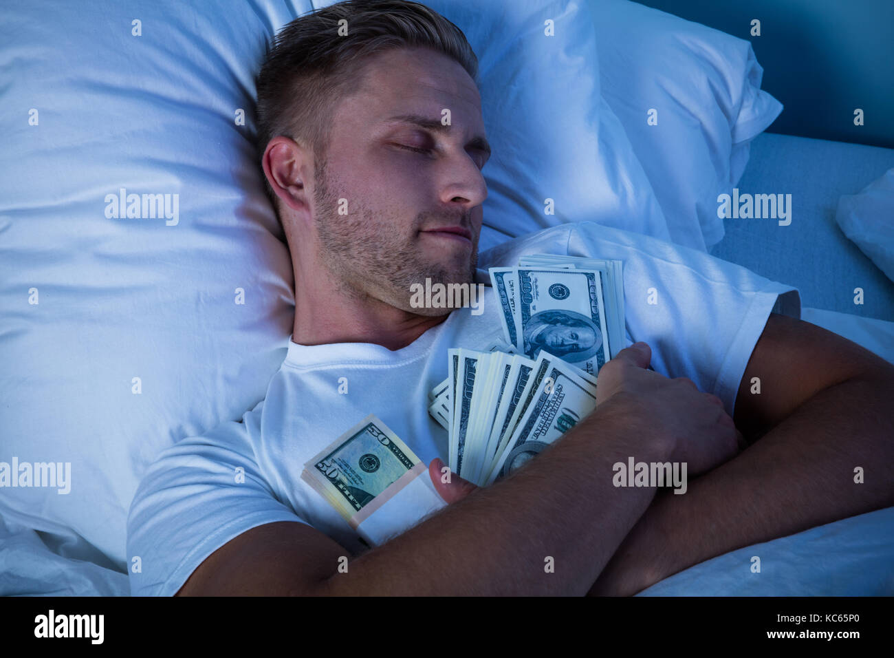 Uomo dorme sul letto con fascio di moneta note Foto Stock