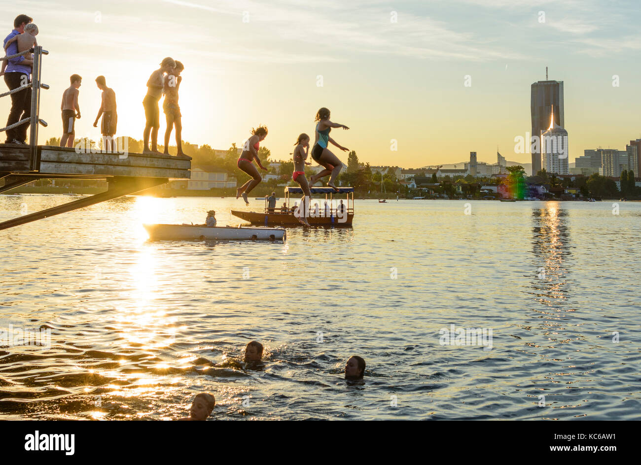 Bambini, bambini saltare in acqua, fiume Alte Donau (Vecchio Danubio), skyline di Donaucity, DC Tower 1, barche, Wien, Vienna, 22. Donaustadt, Wien, Austria Foto Stock