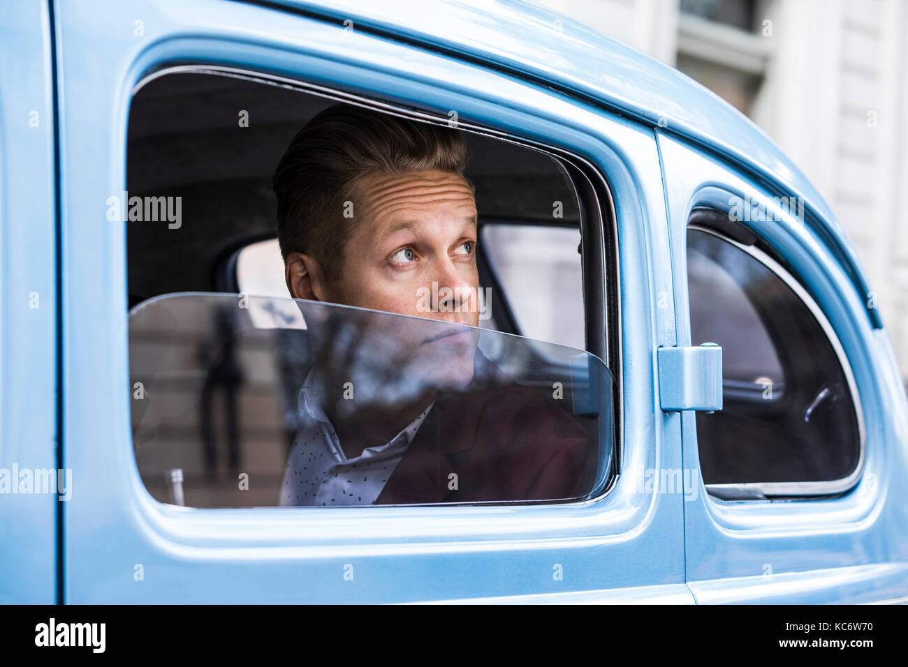 Uomo che guarda attraverso la finestrella in auto rétro Foto Stock