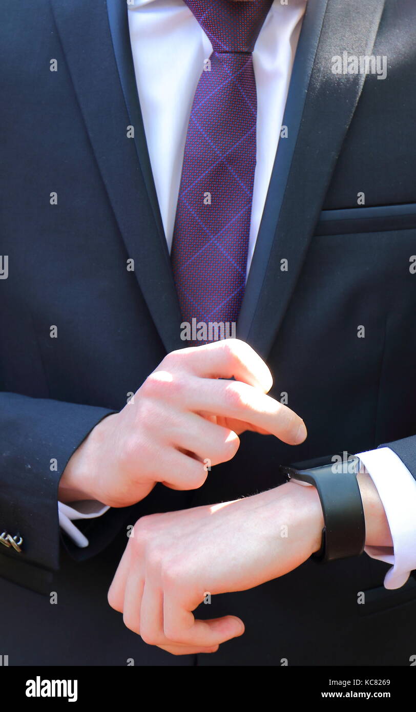 Close-up vista frontale di una persona in un abito scuro, una camicia  bianca e una cravatta viola l'impostazione di un orologio nero in formato  verticale Foto stock - Alamy